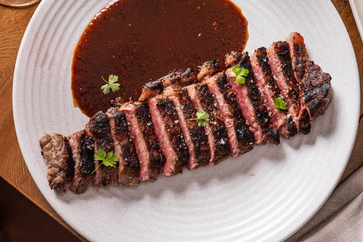 Tommy's Angus sirloin steak with birria sauce, chat potatoes and a cocktail